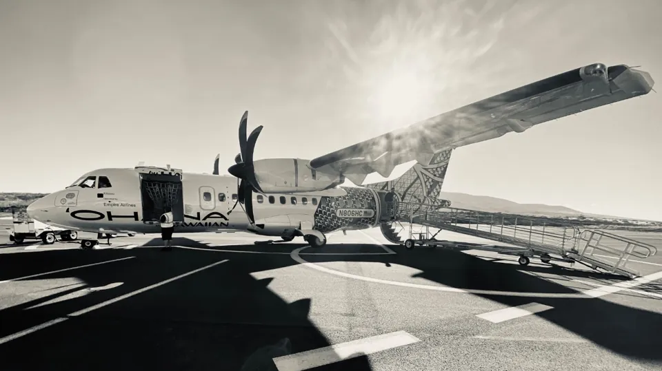 A propeller plane on a sunlit airfield